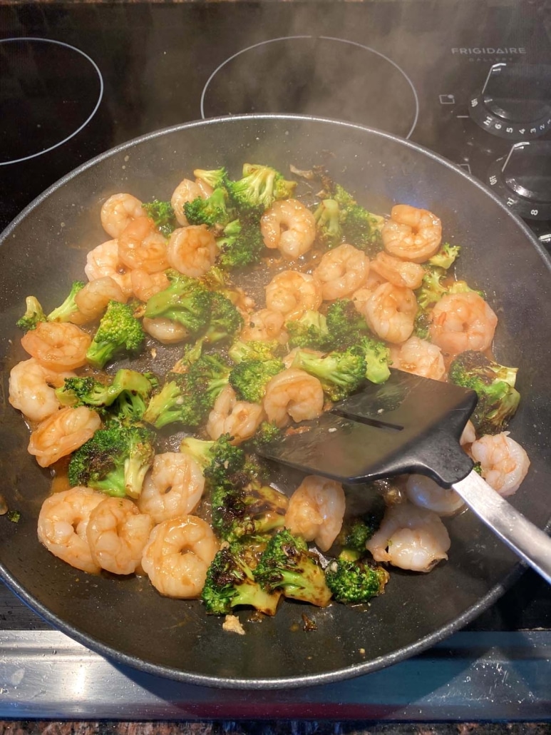 spatula stirring up shrimp and broccoli stir fry dinner