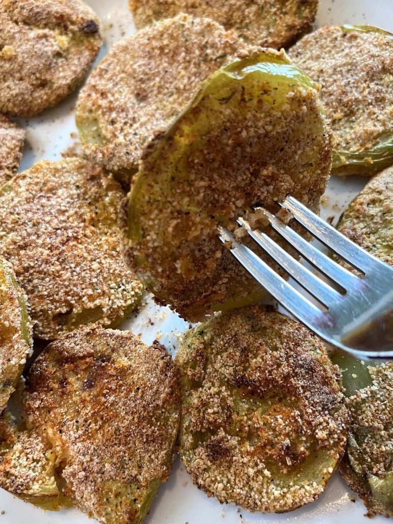 fork holding one sliced tomato, coated in breadcrumbs, and cooked in air fryer