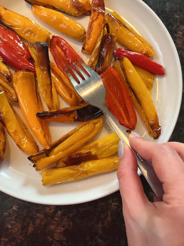 hand holding fork with piece of cooked mini pepper