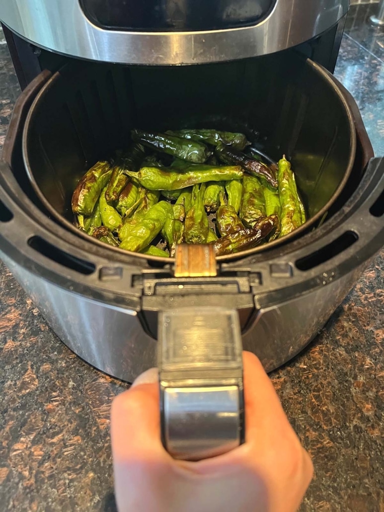 air fryer opened to show Shishito Peppers cooking inside