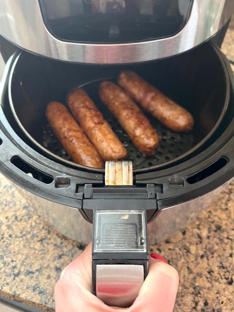 air fryer opened to show Beyond Sausages cooking inside