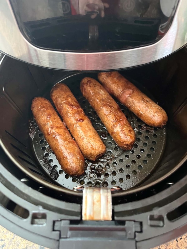 air fryer opened to show plant-based sausages inside