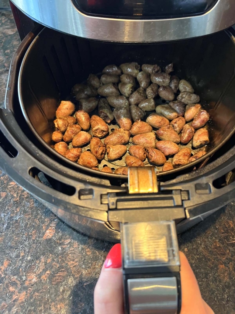 air fryer opened to show tender and seasoned chicken hearts