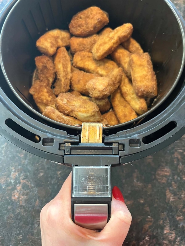 hand holding air fryer basket with churros inside