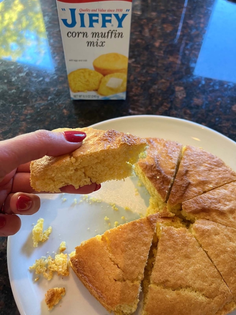 hand holding piece of Air Fryer Cornbread next to a package of Jiffy corn muffin mix