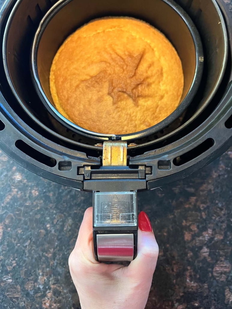 hand holding air fryer basket with baked cornbread inside