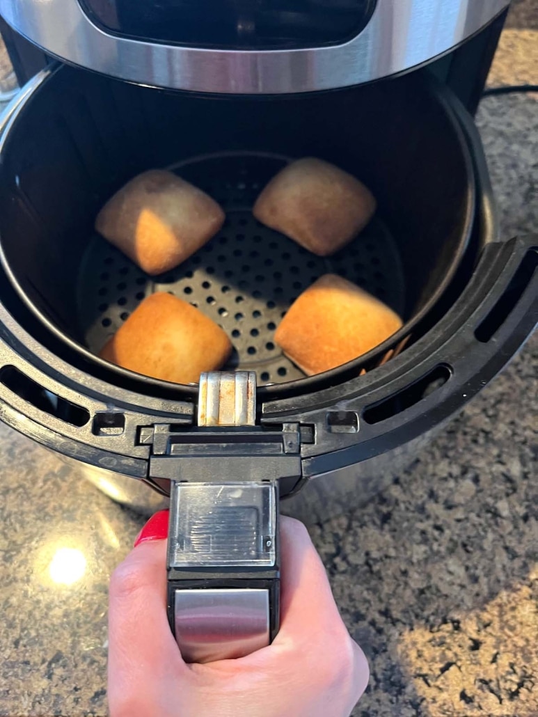 air fryer opened to show dinner rolls inside