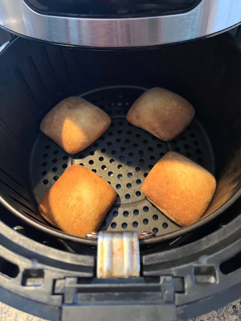 air fryer opened to show golden brown dinner rolls inside