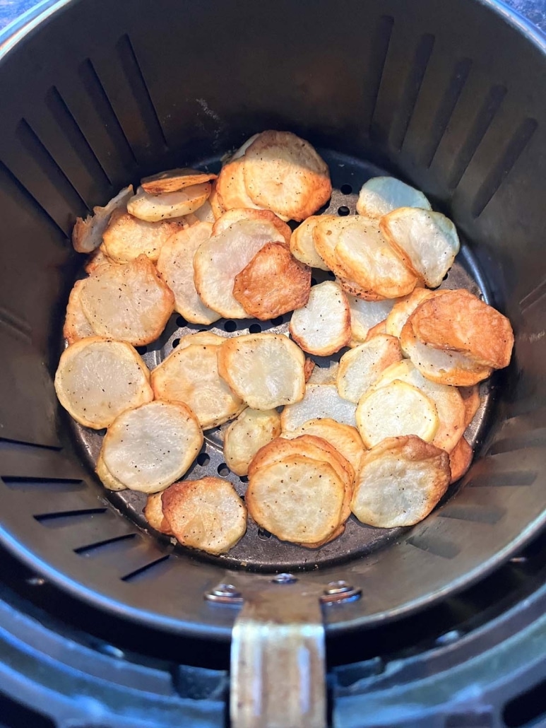 inside of air fryer basket with sliced potatoes