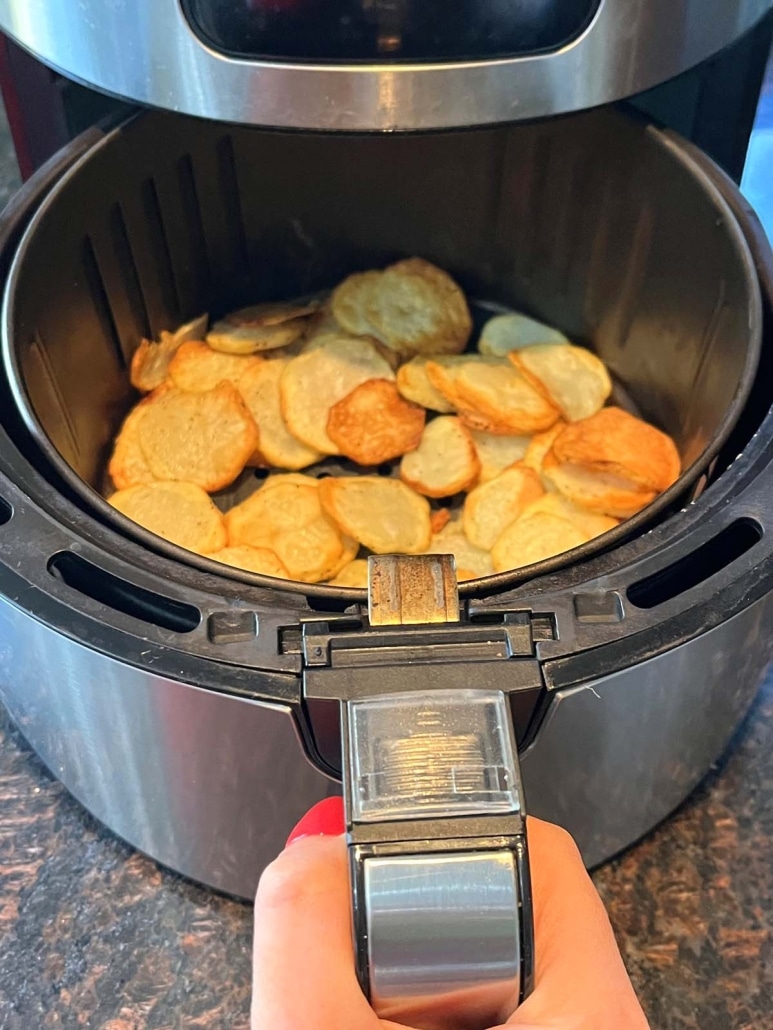 air fryer opened to show sliced potatoes cooking inside