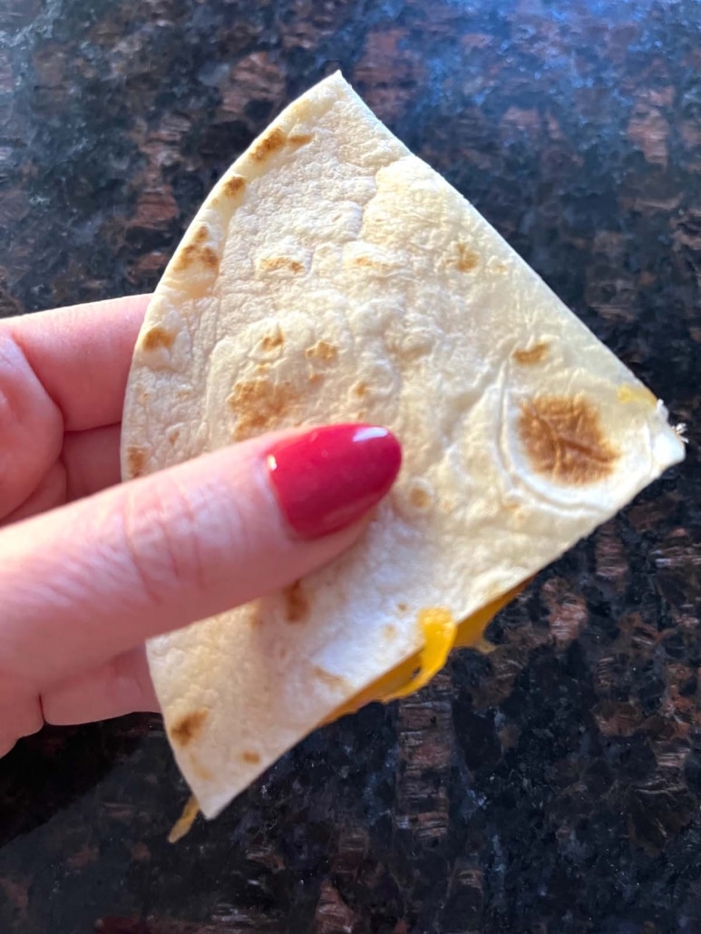 hand holding a corner of the Microwave Cheese Quesadilla