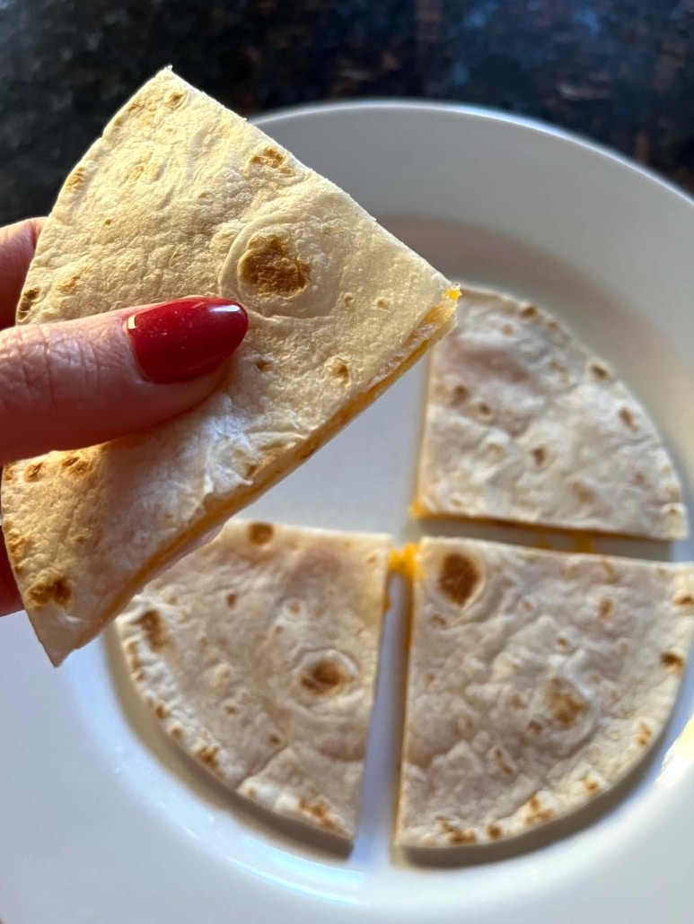 hand holding a slice of easy side dish Microwave Cheese Quesadilla