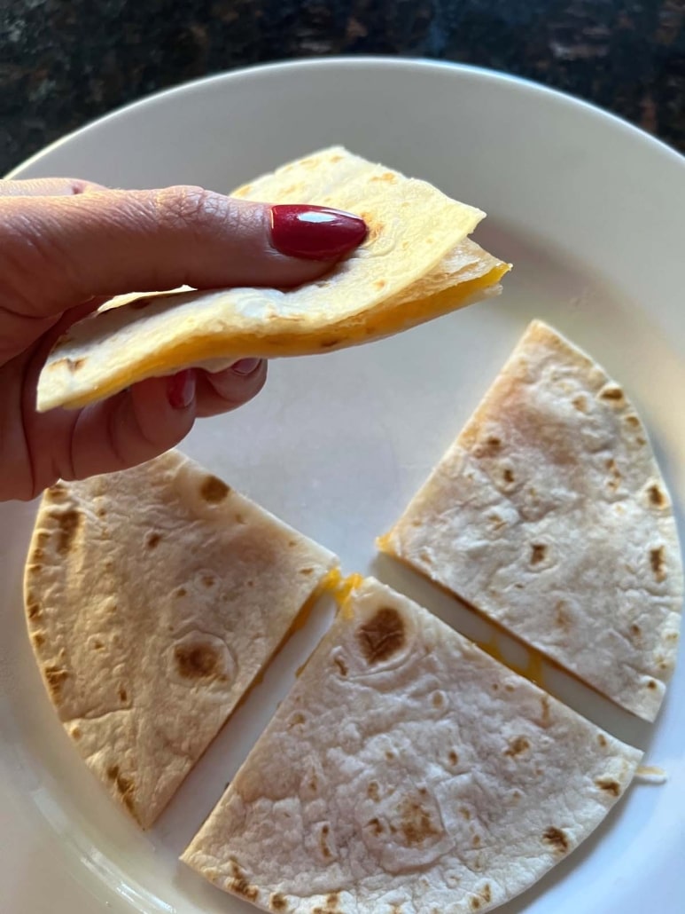 hand holding piece of Microwave Cheese Quesadilla