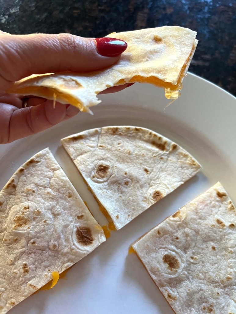 hand holding Microwave Cheese Quesadilla with a bite taken out