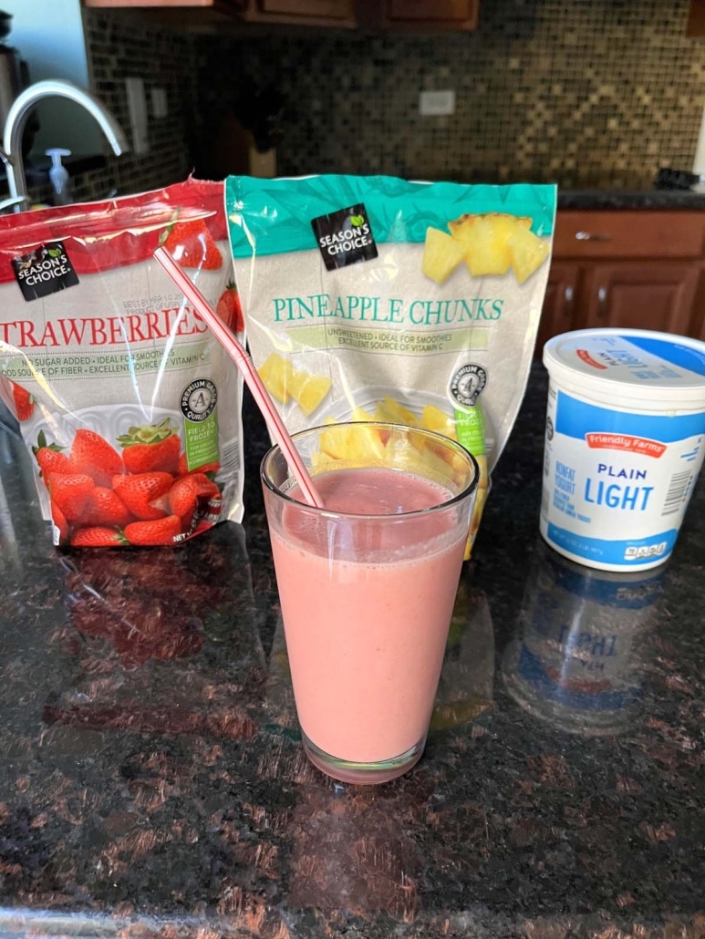 frozen strawberries, frozen pineapple, and yogurt next to a strawberry pineapple smoothie