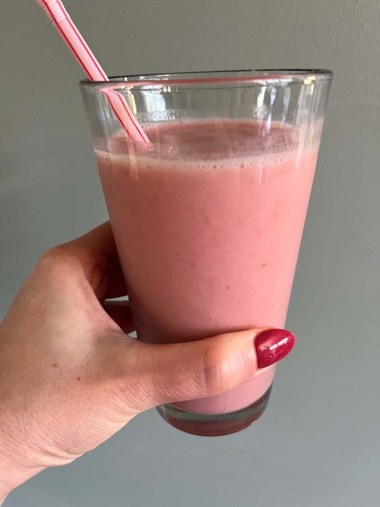 hand holding Strawberry Pineapple Smoothie with a straw