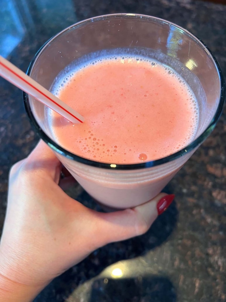 hand holding glass of strawberry pineapple smoothie