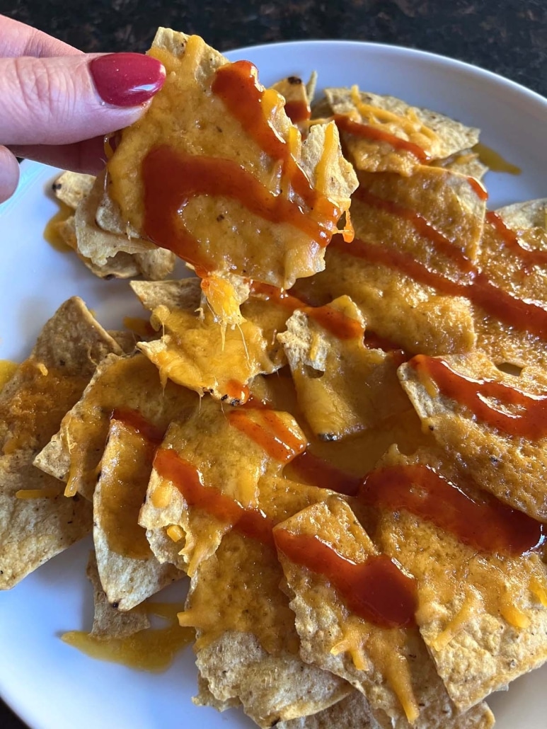 hand holding Microwave Nacho with hot sauce