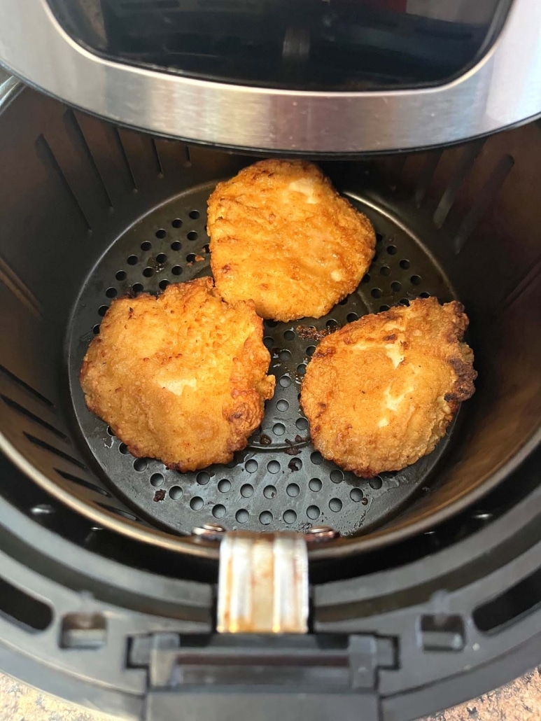 air fryer opened to show crispy Aldi chicken fillets cooking inside