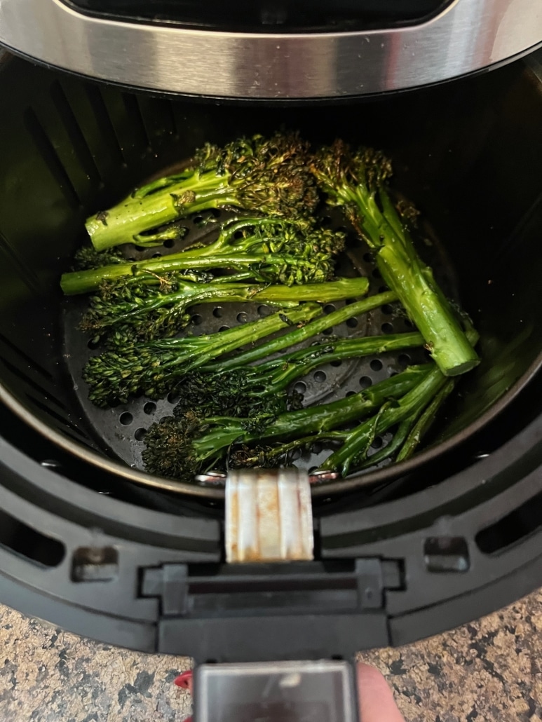 seasoned broccolini cooking inside an air fryer