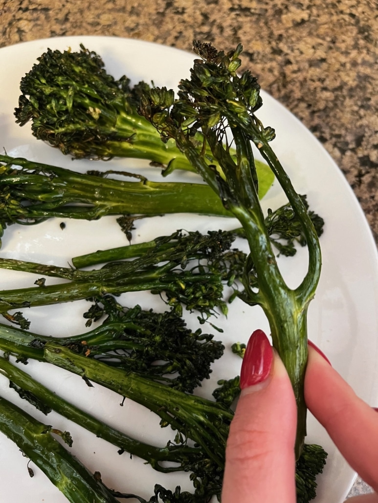 hand holding piece of air fryer broccolini