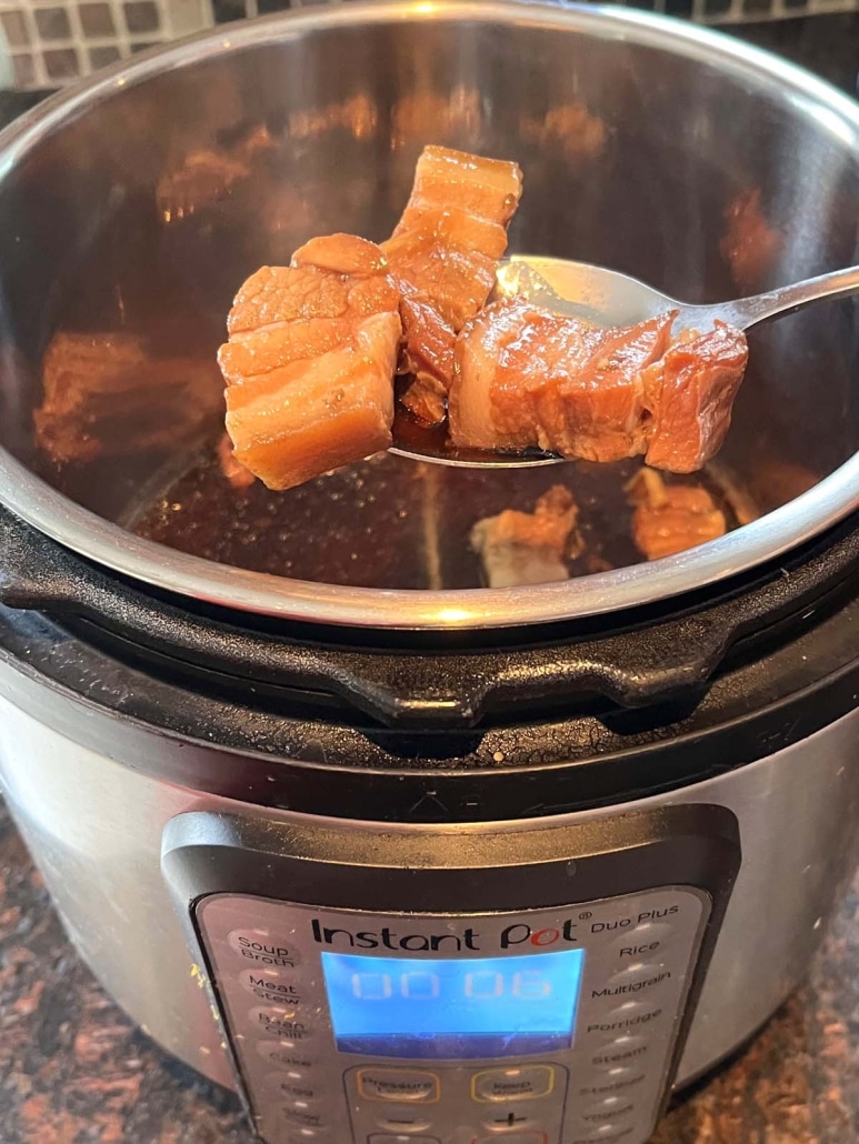 scooping out cooked pork belly from instant pot