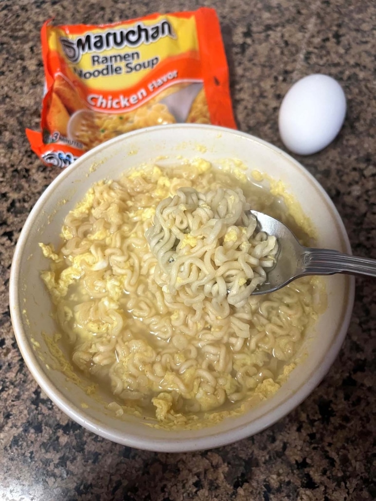 bowl of ramen soup next to a packet of ramen and an egg