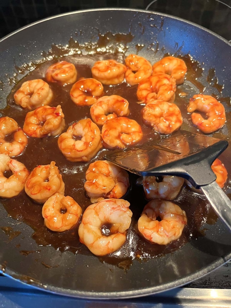 spatula stirring up shrimp in teriyaki sauce