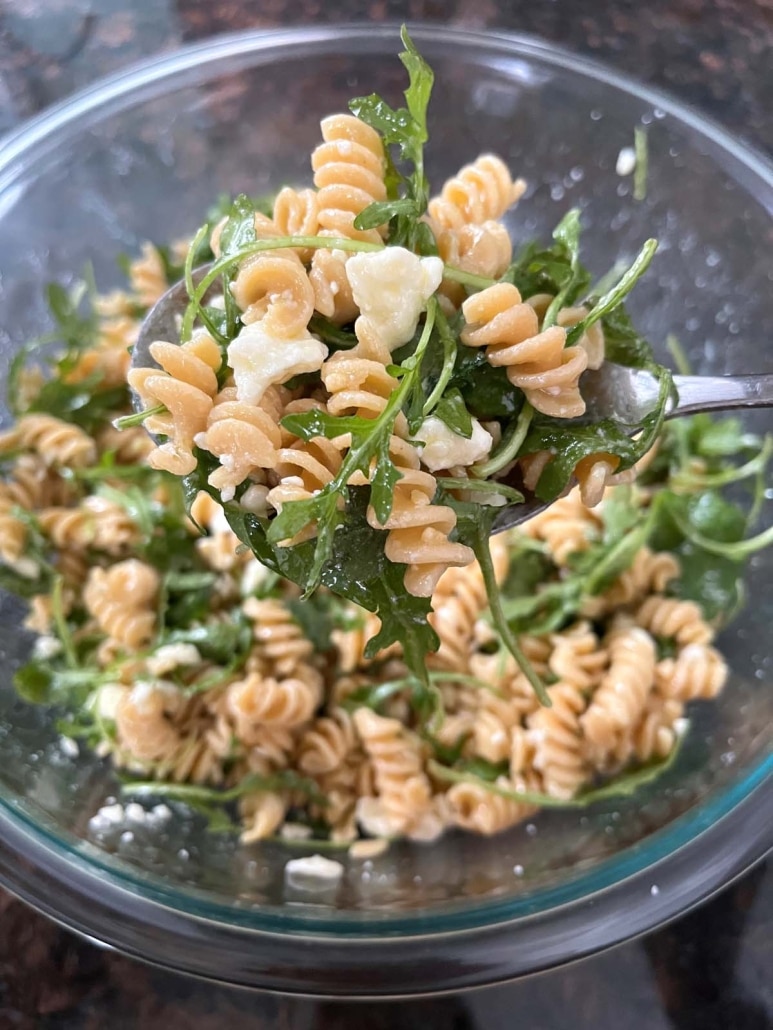 tossing together Arugula Pasta Salad in a bowl