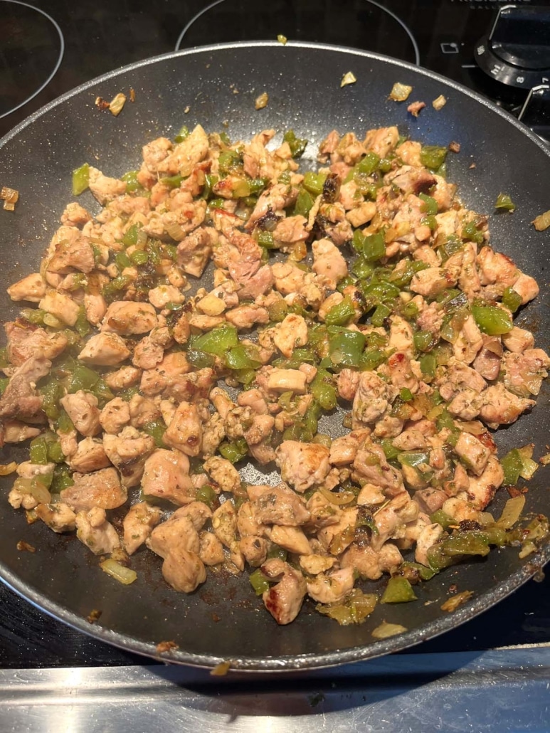 seasoned and diced chicken, pepper, and onion in a skillet