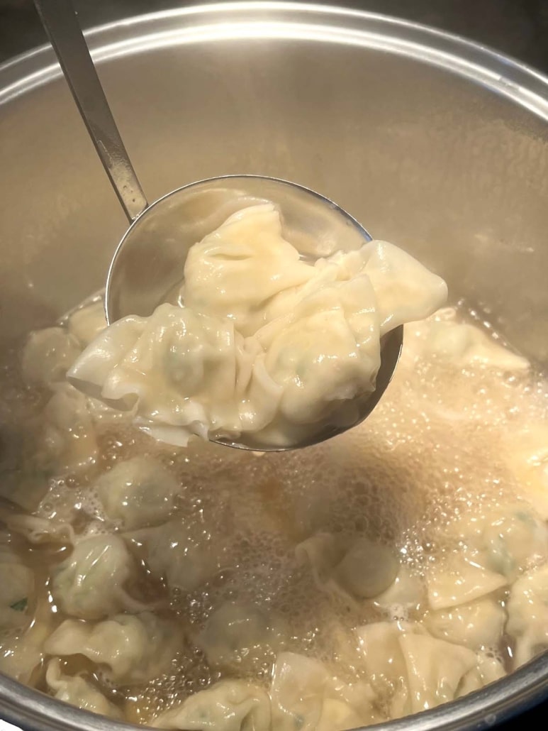 large spoon scooping mini wontons out of Dumpling Soup