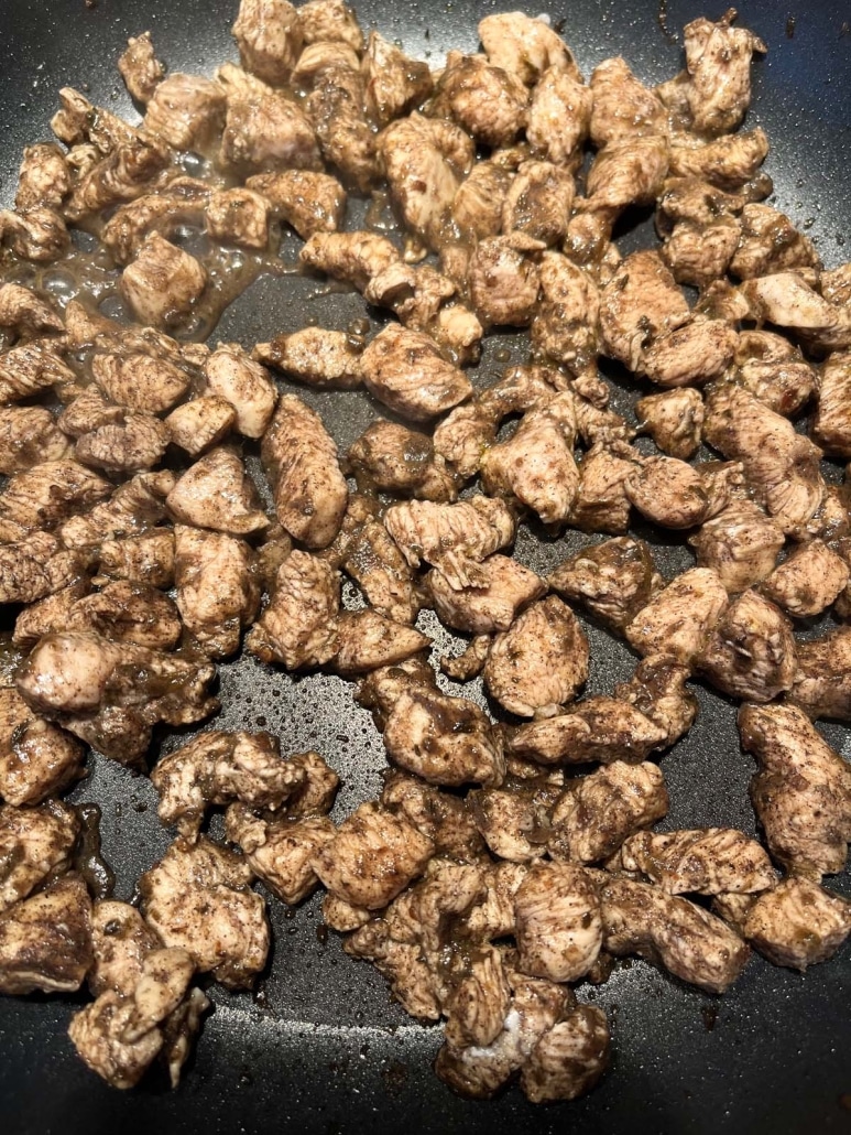 jerk spice seasoned chicken cooking in a skillet