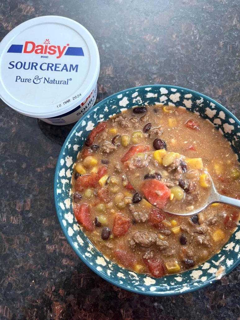 bowl of Santa Fe Soup next to a container of sour cream