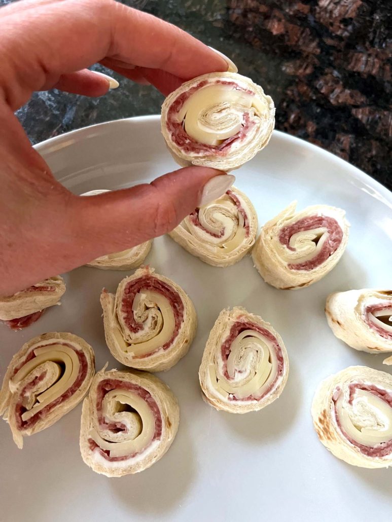 hand holding an Italian Pinwheel With Salami And Cream Cheese