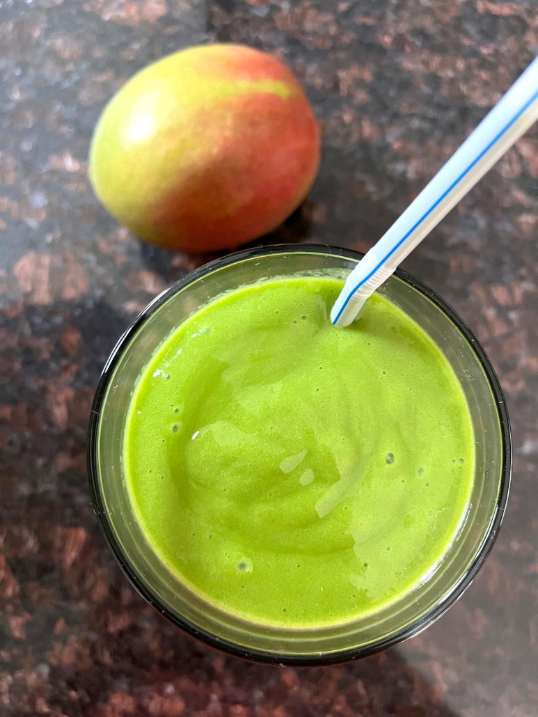 glass of Mango Spinach Smoothie next to a ripe mango