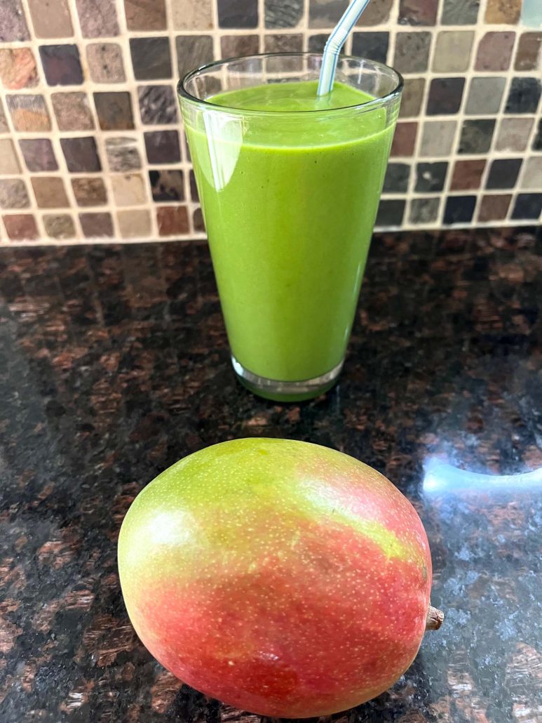 glass of Mango Spinach Smoothie next to a mango