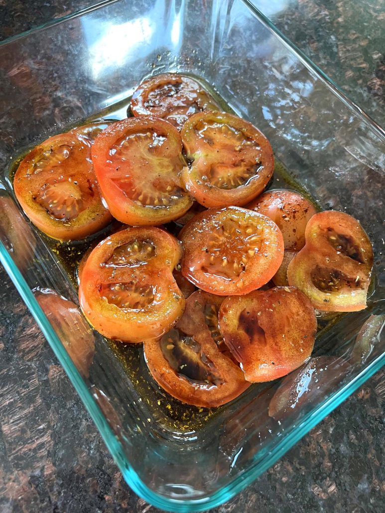 glass dish on countertop with marinating tomatoes inside