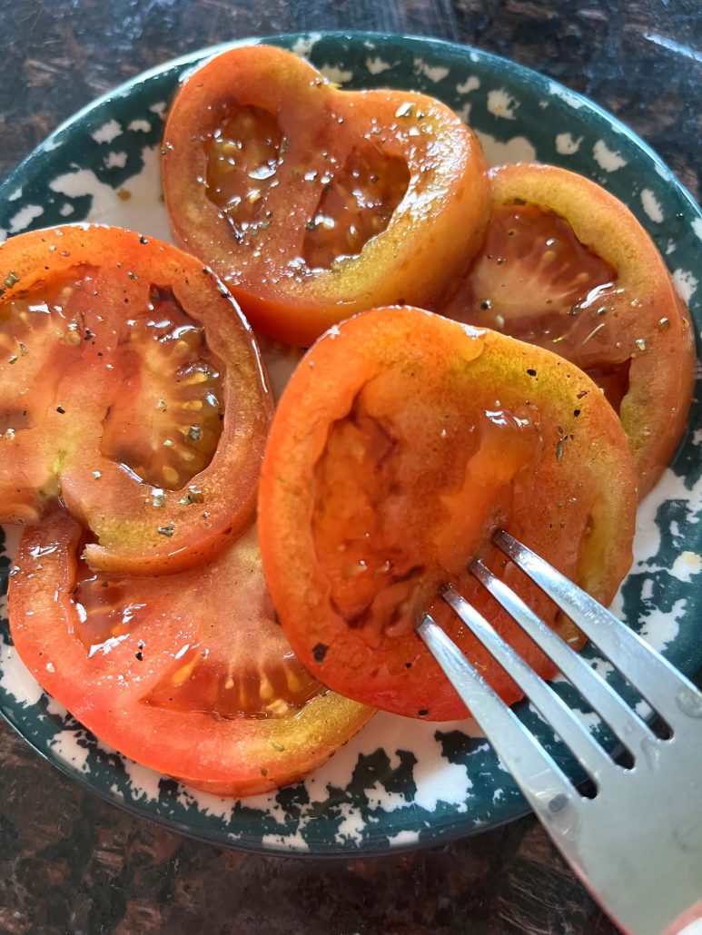 fork holding slice of marinated tomato