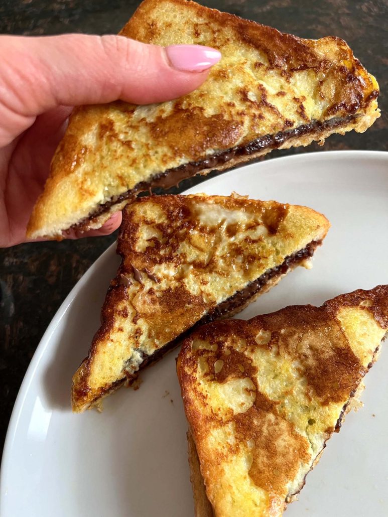 hand holding slice of French toast with Nutella in it