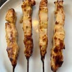 Top view of four pcs of air fried chicken breast skewers from Aldi on a white plate.