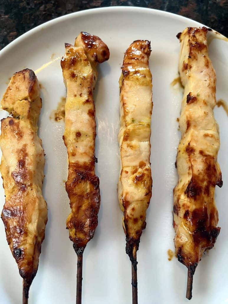 Chicken breast skewers with a golden finish on a white plate.