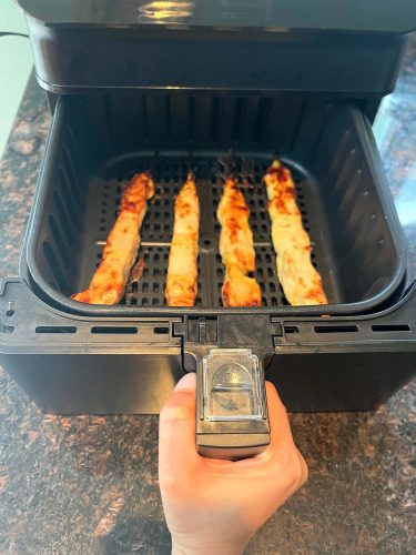 Four aldi chicken breast skewers inside of a open basket air fryer.