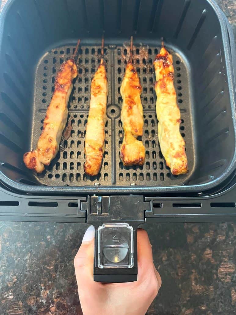 Four skewers of chicken breast inside of a air fryer.