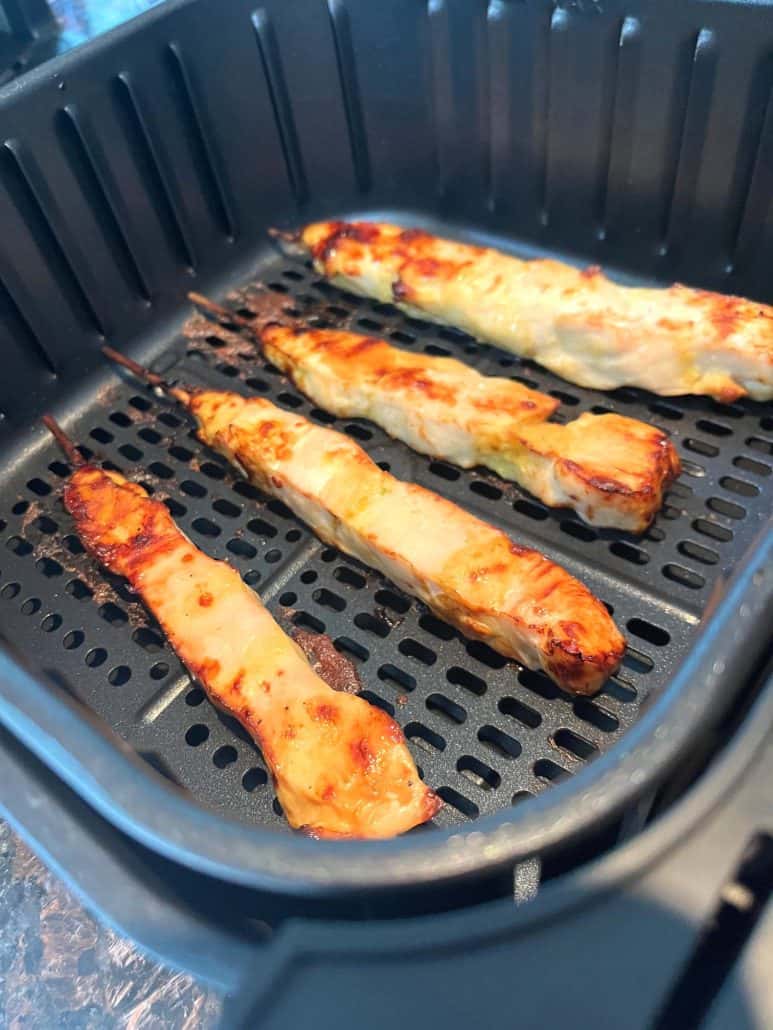 Four chicken skewers inside an air fryer basket. 