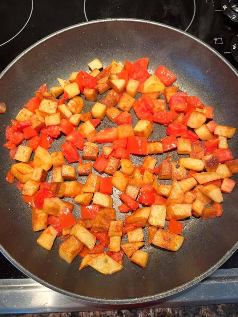 Top view of fried potatoes and tomatoes on a non-sticky pan.