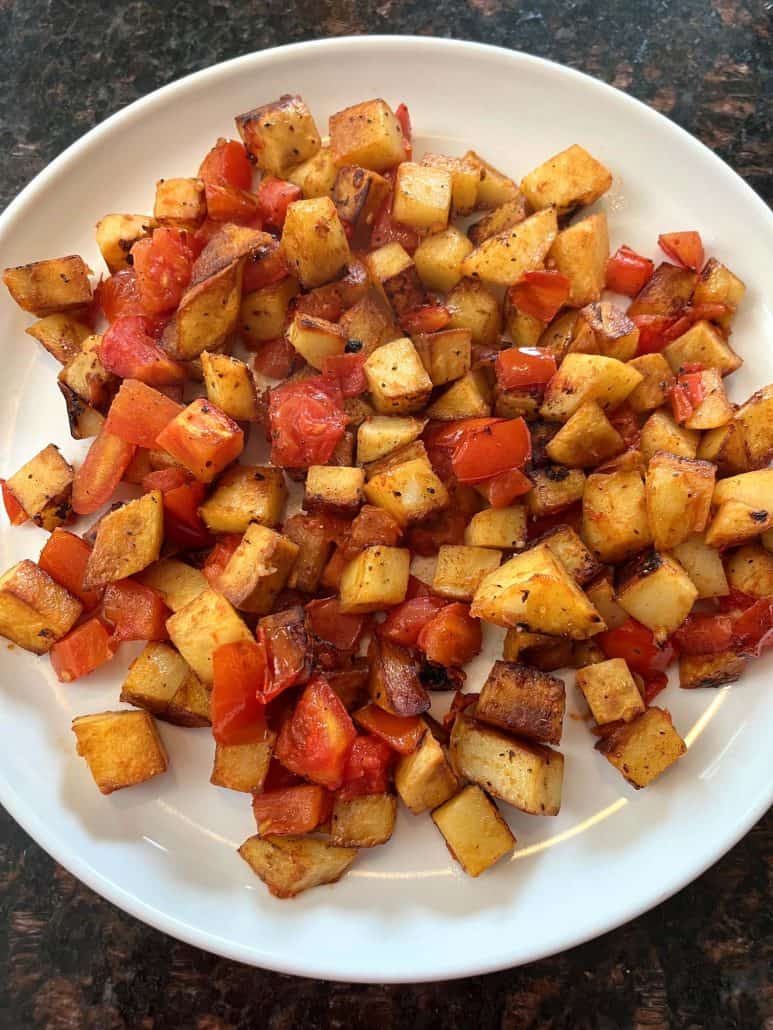 Top view of fried potatoes and tomatoes.