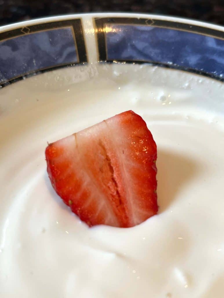 Yogurt fruit dip in close-up with strawberry slices,.