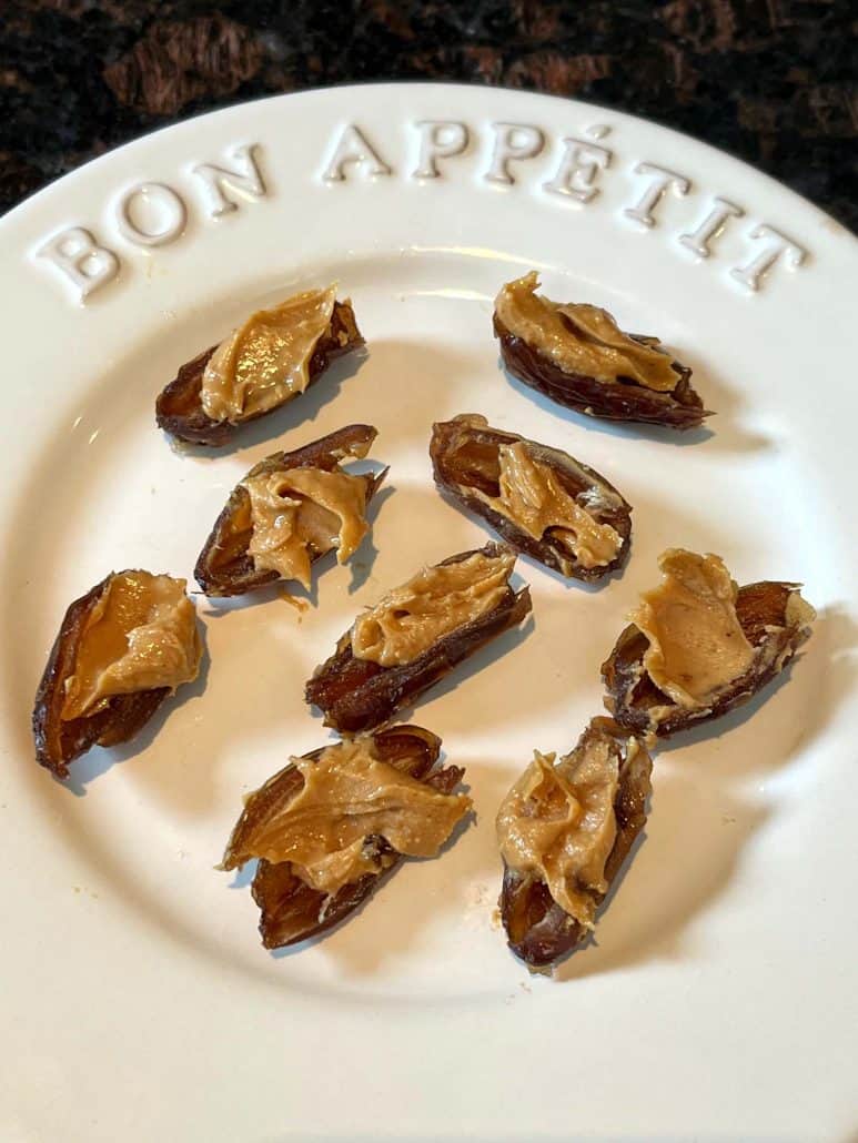 Top view of peanut butter-stuffed dates arranged on a white plate.