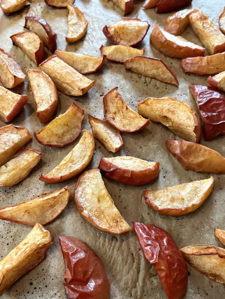 Golden-brown roasted apples on a parchment paper with a soft, juicy interior.