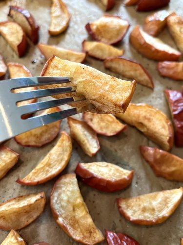 Roasted apples with a golden, caramelized exterior arranged on a plate, highlighting their soft, tender texture.